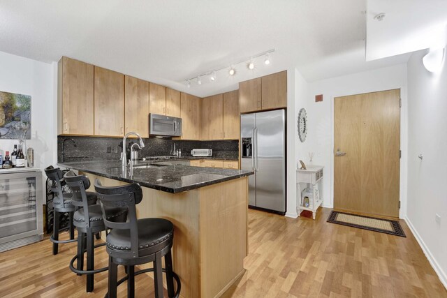 9725 Woods Dr Unit 507, Skokie, IL 60077 - kitchen with appliances with stainless steel finishes, wine cooler, a peninsula, light wood-style flooring, and a breakfast bar area