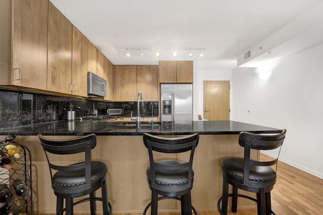9725 Woods Dr Unit 507, Skokie, IL 60077 - kitchen featuring stainless steel appliances, a sink, a peninsula, decorative backsplash, and a kitchen breakfast bar