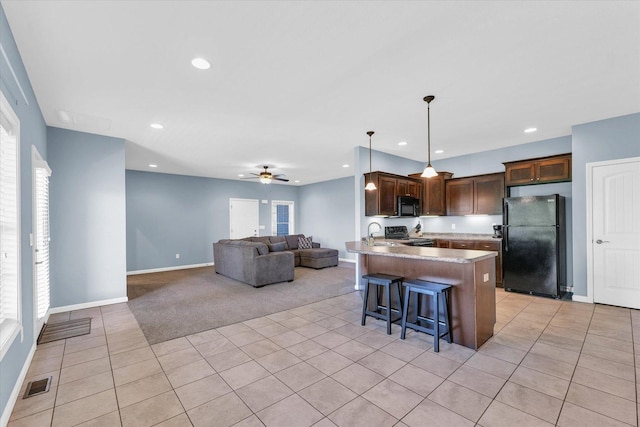 kitchen featuring black appliances, light tile patterned floors, a peninsula, a kitchen bar, and open floor plan