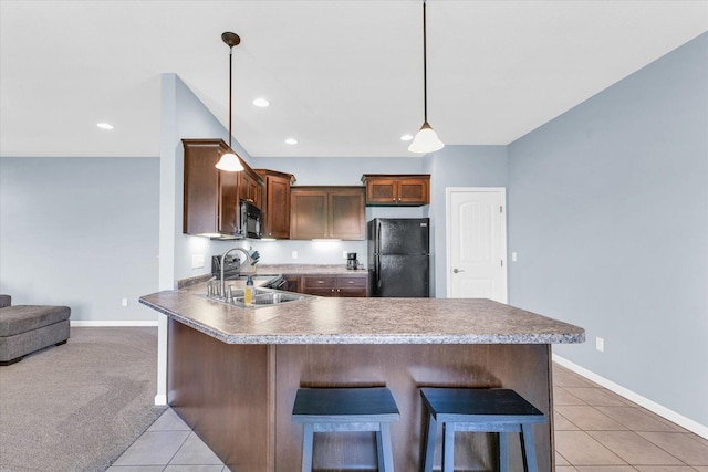 kitchen with black appliances, a sink, a peninsula, light tile patterned flooring, and a breakfast bar area