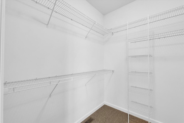 walk in closet featuring dark carpet