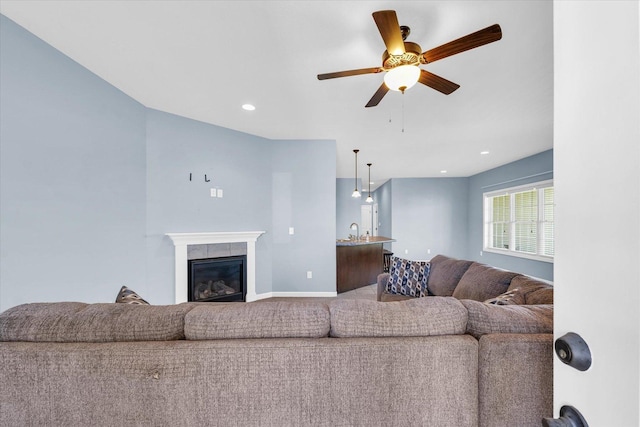 living room featuring ceiling fan, a glass covered fireplace, baseboards, and recessed lighting