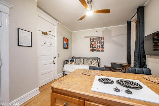 bedroom featuring light wood-style flooring, baseboards, ornamental molding, and a ceiling fan