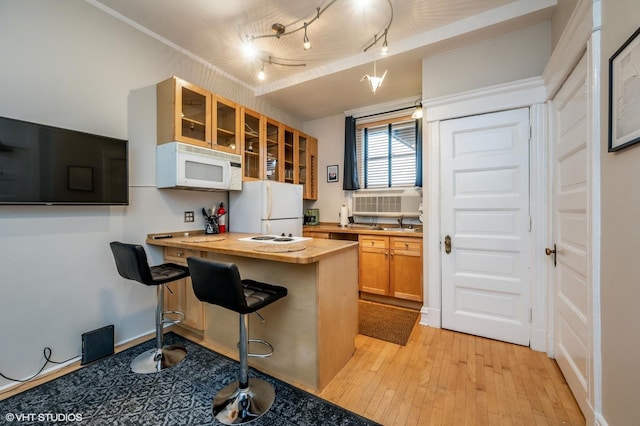 kitchen with white appliances, butcher block counters, glass insert cabinets, light wood-style flooring, and a peninsula