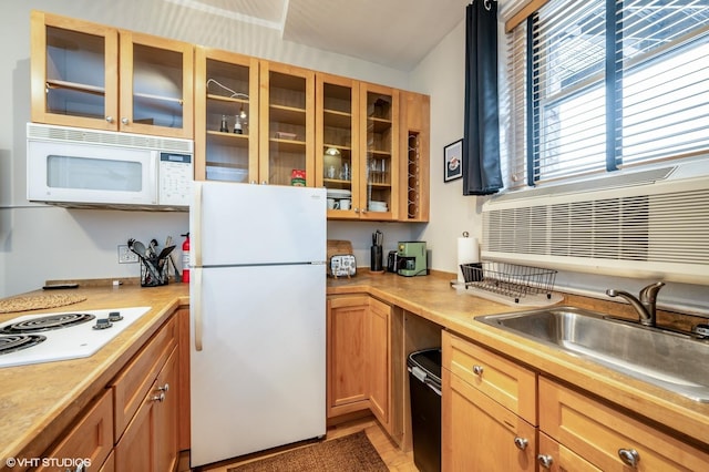 kitchen with white appliances, light countertops, glass insert cabinets, a sink, and brown cabinets