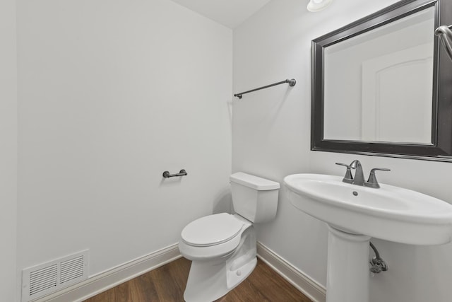 bathroom featuring baseboards, wood finished floors, toilet, and a sink