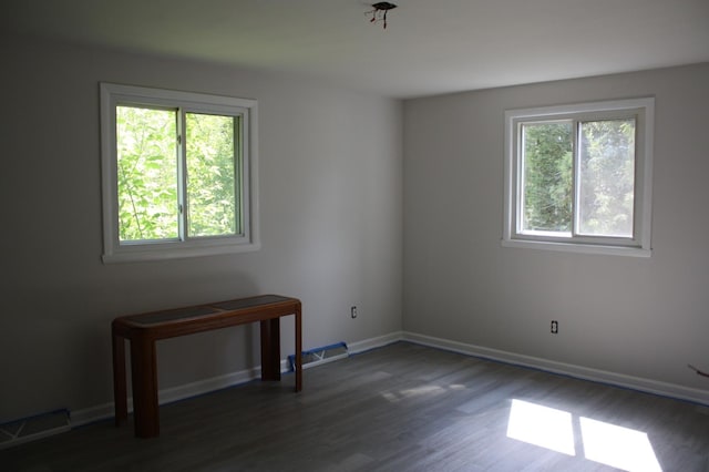 unfurnished room featuring plenty of natural light, wood finished floors, and baseboards