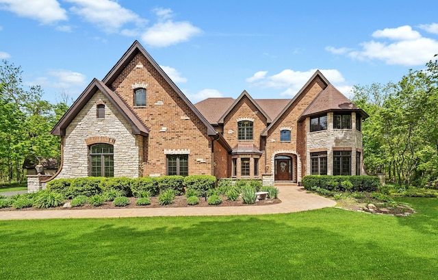 view of front of home featuring a front yard, brick siding, and stone siding