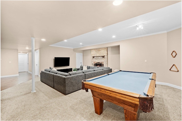 recreation room featuring light colored carpet, baseboards, a stone fireplace, crown molding, and recessed lighting