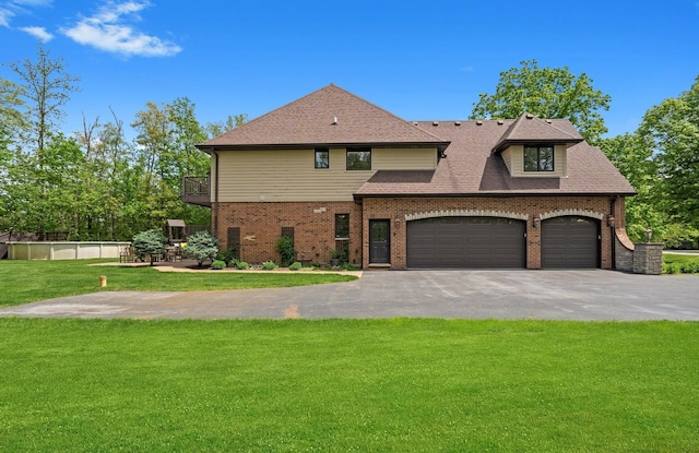 view of front of home with asphalt driveway, a front yard, brick siding, an attached garage, and a balcony