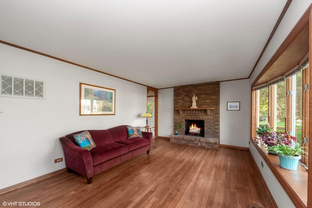 living area featuring light wood-style floors, crown molding, a brick fireplace, and baseboards