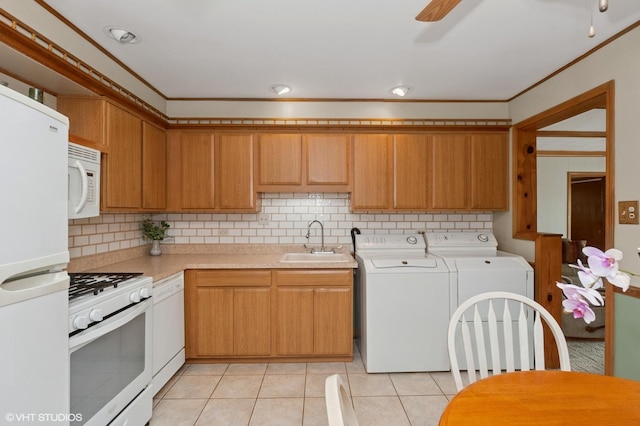 kitchen with white appliances, a sink, washing machine and clothes dryer, light countertops, and backsplash
