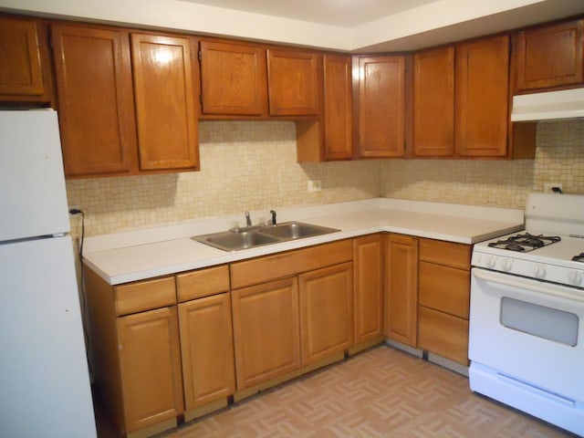 kitchen featuring white appliances, under cabinet range hood, a sink, and light countertops