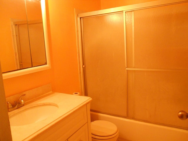 bathroom with toilet, vanity, and combined bath / shower with glass door