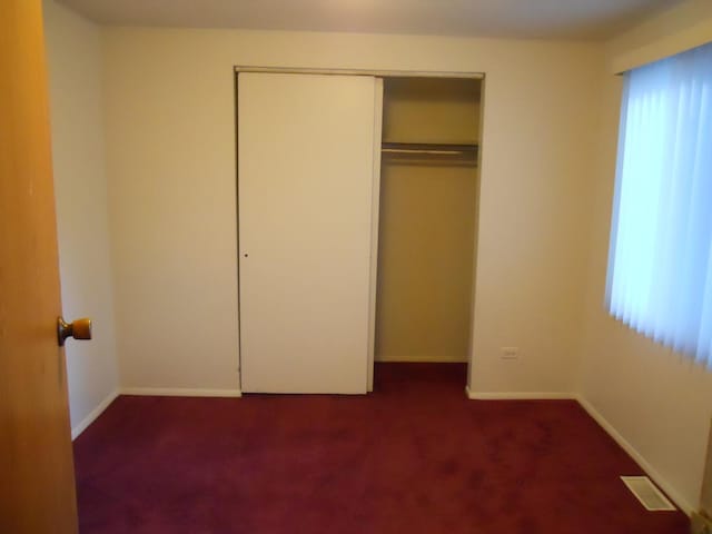 unfurnished bedroom with a closet, carpet, and baseboards