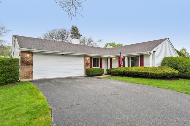 ranch-style home with a garage, asphalt driveway, brick siding, a chimney, and roof with shingles