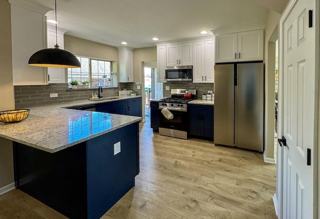 kitchen featuring appliances with stainless steel finishes, a sink, white cabinetry, light wood-type flooring, and recessed lighting