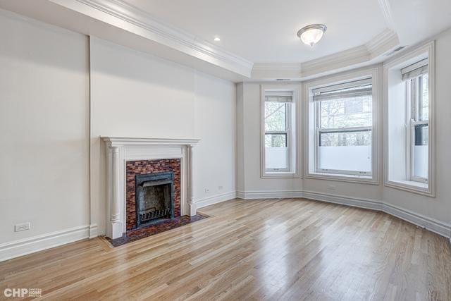 unfurnished living room featuring a raised ceiling, crown molding, wood finished floors, baseboards, and a fireplace with flush hearth