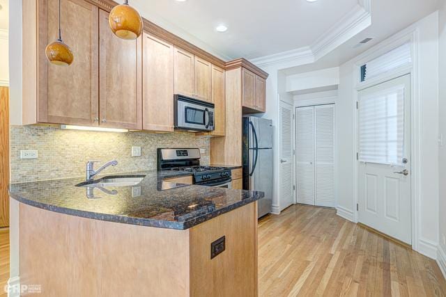 kitchen with stainless steel appliances, light wood-style flooring, a sink, decorative backsplash, and dark stone counters