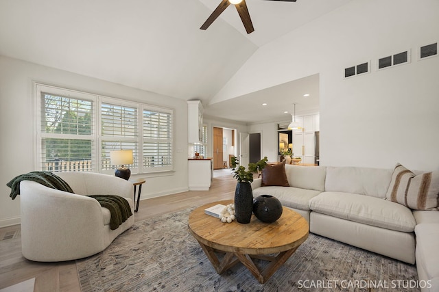 living room with vaulted ceiling, a ceiling fan, baseboards, and light wood-style floors
