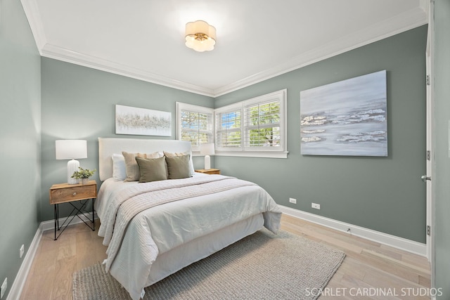 bedroom with ornamental molding, light wood finished floors, and baseboards
