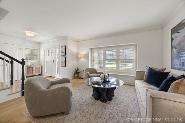 living area featuring stairs, plenty of natural light, wood finished floors, and crown molding