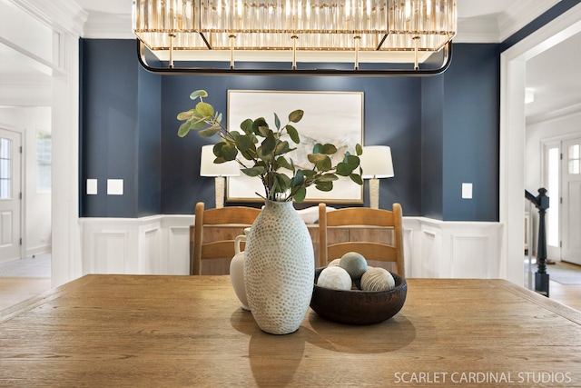 dining area with a decorative wall, wainscoting, and crown molding