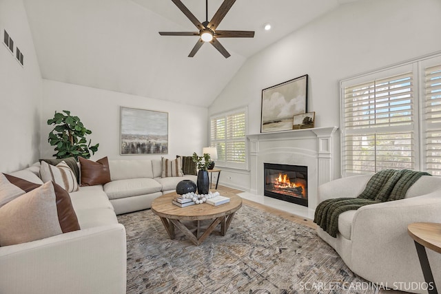 living room featuring a glass covered fireplace, ceiling fan, wood finished floors, recessed lighting, and high vaulted ceiling