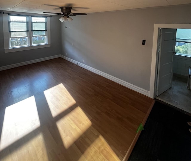 spare room with a ceiling fan, wood finished floors, and baseboards