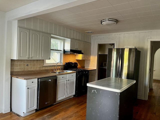 kitchen featuring stainless steel appliances, a sink, under cabinet range hood, and dark wood-style flooring