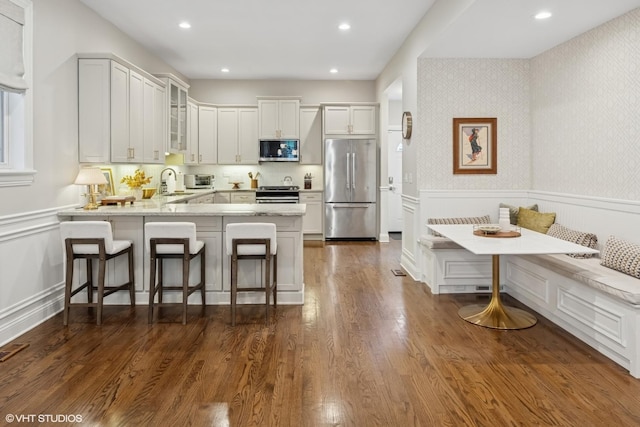1319 N Oakley Blvd, Chicago, IL 60622 - kitchen featuring appliances with stainless steel finishes, breakfast area, a peninsula, glass insert cabinets, and a wainscoted wall