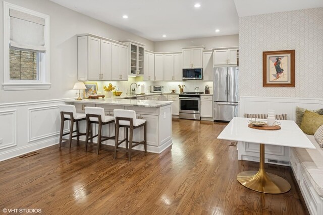 1319 N Oakley Blvd, Chicago, IL 60622 - kitchen with appliances with stainless steel finishes, wallpapered walls, a peninsula, glass insert cabinets, and a wainscoted wall