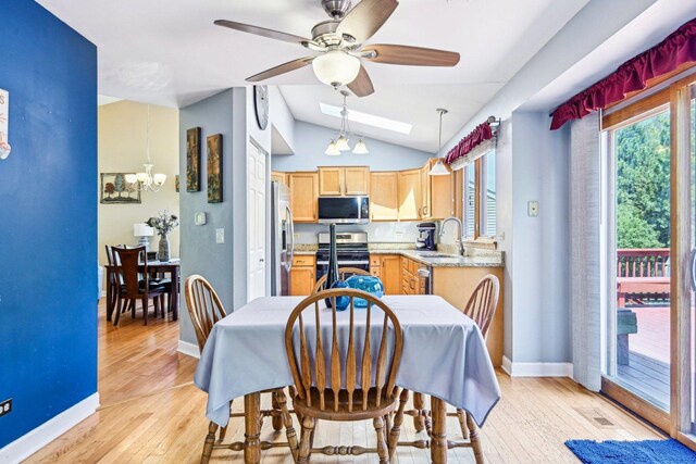 dining area with baseboards, vaulted ceiling, light wood-type flooring, a chandelier, and ceiling fan