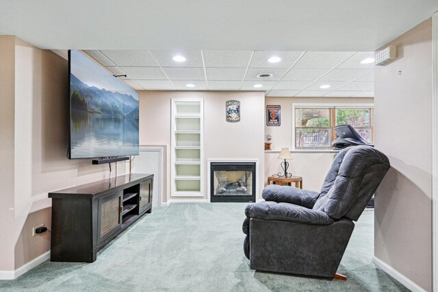 living area with carpet, recessed lighting, a drop ceiling, baseboards, and a glass covered fireplace