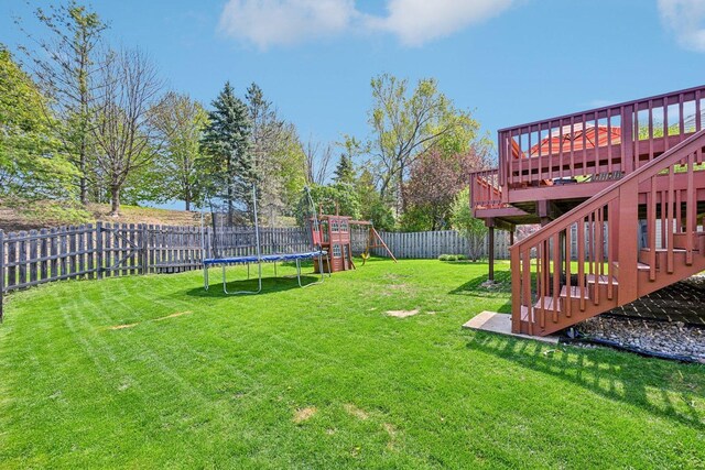 view of yard with a playground, a trampoline, a deck, and stairway