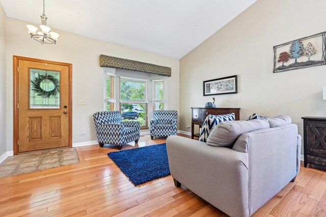 living area featuring a chandelier, baseboards, light wood-style flooring, and high vaulted ceiling