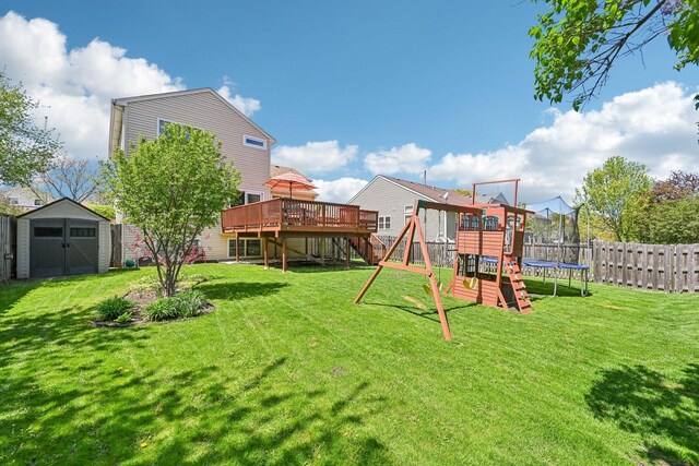 view of yard with a storage shed, a trampoline, a playground, a deck, and an outbuilding
