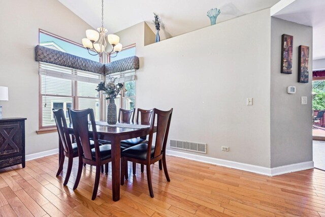 dining room with a chandelier, wood-type flooring, baseboards, and high vaulted ceiling