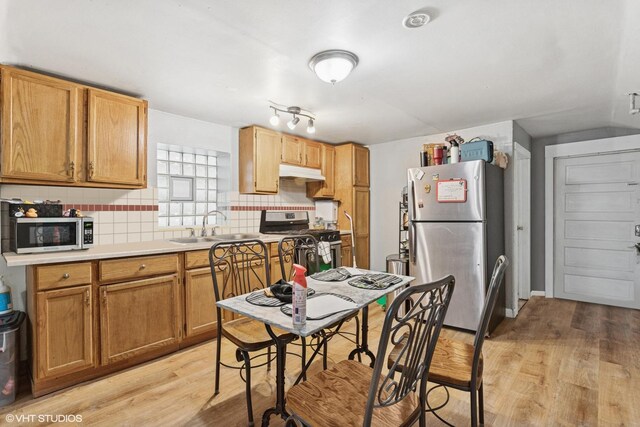 2416 N Avers Ave, Chicago, IL 60647 - kitchen with appliances with stainless steel finishes, a sink, light wood-style flooring, under cabinet range hood, and decorative backsplash