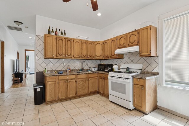 2416 N Avers Ave, Chicago, IL 60647 - kitchen featuring white gas range oven, under cabinet range hood, backsplash, light tile patterned floors, and ceiling fan