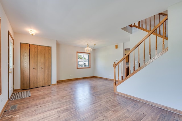 2675 Dorothy Dr, Aurora, IL 60504 - unfurnished living room with stairway, a chandelier, light wood-style floors, and baseboards