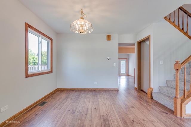 2675 Dorothy Dr, Aurora, IL 60504 - spare room featuring stairway, a chandelier, light wood-style floors, and baseboards