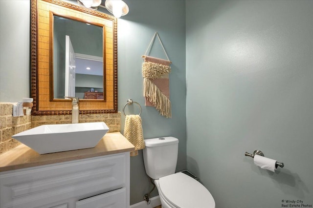 bathroom with tasteful backsplash, toilet, and vanity