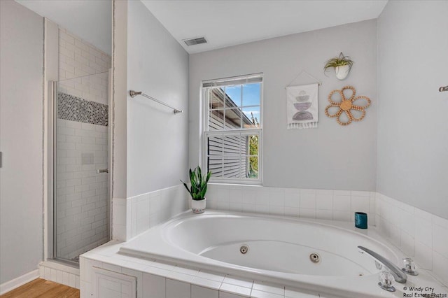 bathroom with a stall shower, a whirlpool tub, and wood finished floors