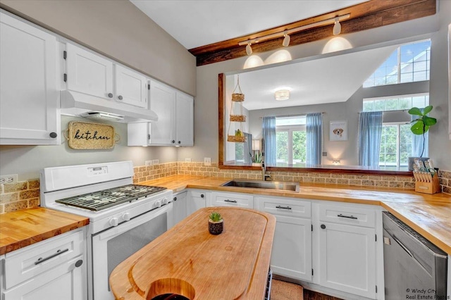 kitchen with gas range gas stove, under cabinet range hood, butcher block counters, dishwasher, and white cabinets