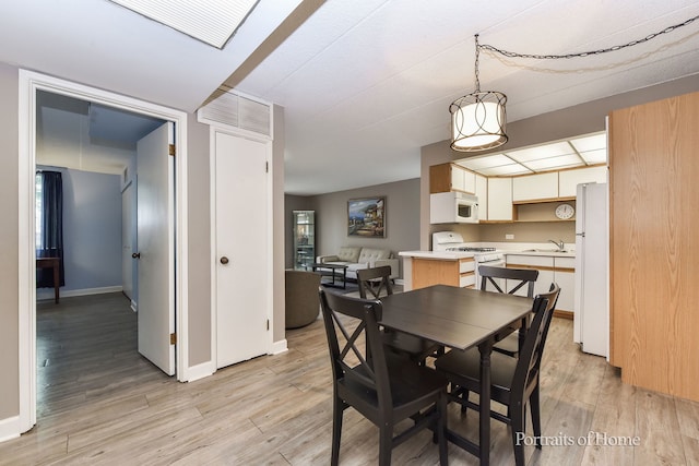 dining space with light wood-style flooring and baseboards