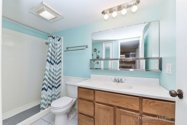full bathroom featuring toilet, vanity, tiled shower, tile patterned floors, and a wainscoted wall