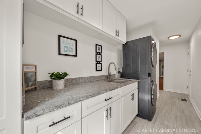 833 Shiloh Cir, Naperville, IL 60540 - kitchen featuring stacked washer / dryer, a sink, white cabinets, baseboards, and light wood-style flooring