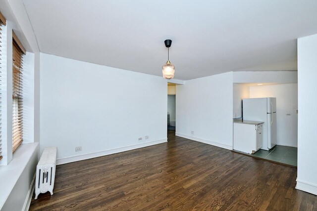 5060 N Claremont Ave Unit 2W, Chicago, IL 60625 - unfurnished living room featuring radiator, dark wood-type flooring, and baseboards