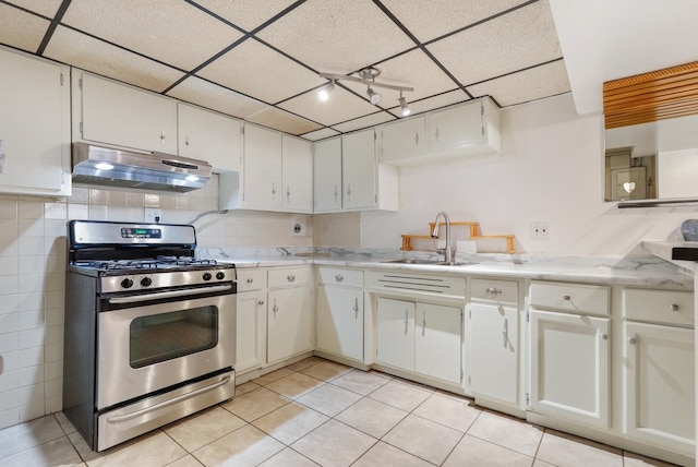 kitchen with stainless steel range with gas stovetop, under cabinet range hood, a sink, light countertops, and a drop ceiling
